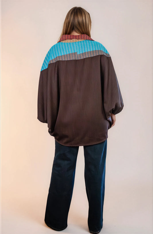 Poncho oversize unisex con cierre al frente y cuello camisero, con azul en espalda alta. Vista de espalda.