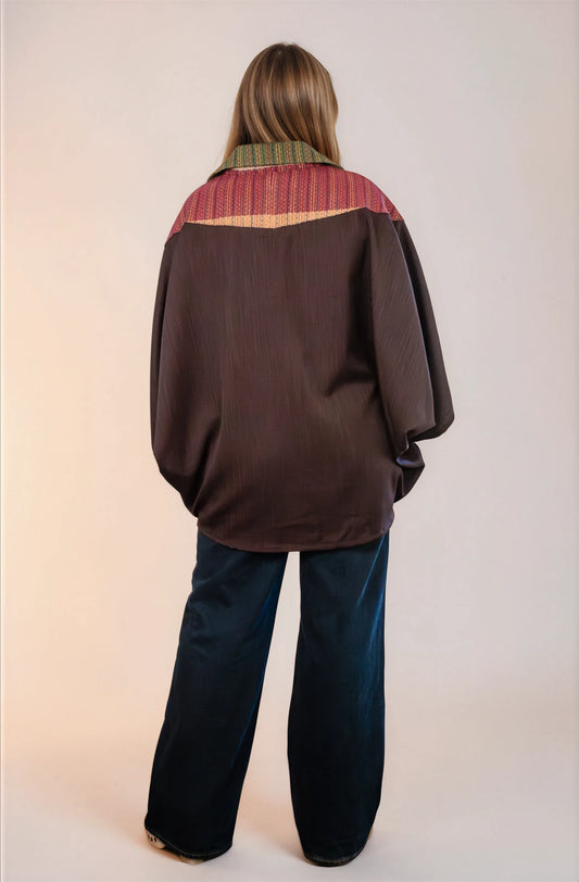 Poncho oversize unisex con cierre al frente y cuello camisero, con guinda en espalda alta. Vista de espalda.