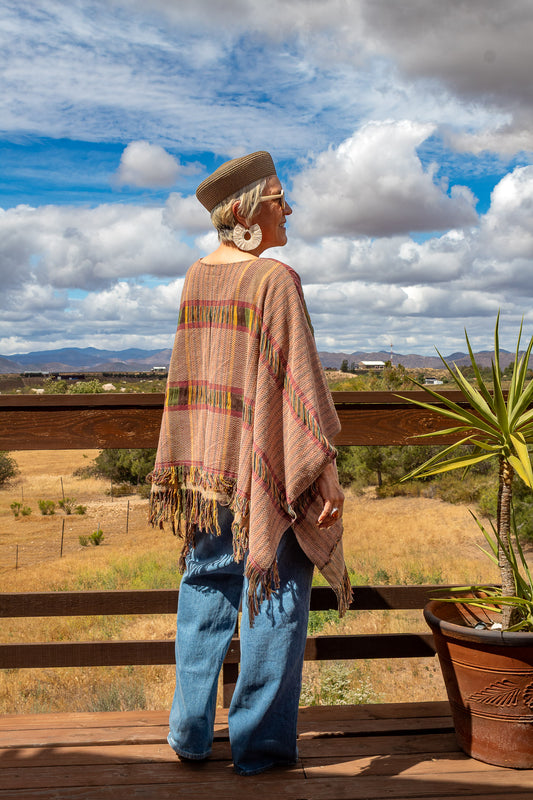 Poncho con textil 100% artesanal tejido en telar de pedal con deshuilados mediano en franjas en todo  lo alto. De corte oversize con cuello en V y flecos en la parte inferior.