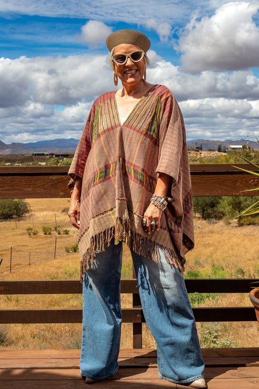 Poncho con textil 100% artesanal tejido en telar de pedal con deshuilados mediano en franjas en todo  lo alto. De corte oversize con cuello en V y flecos en la parte inferior.